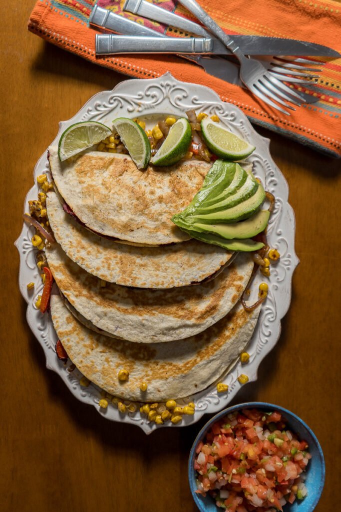 Four flour quesadillas on a white oval plate.