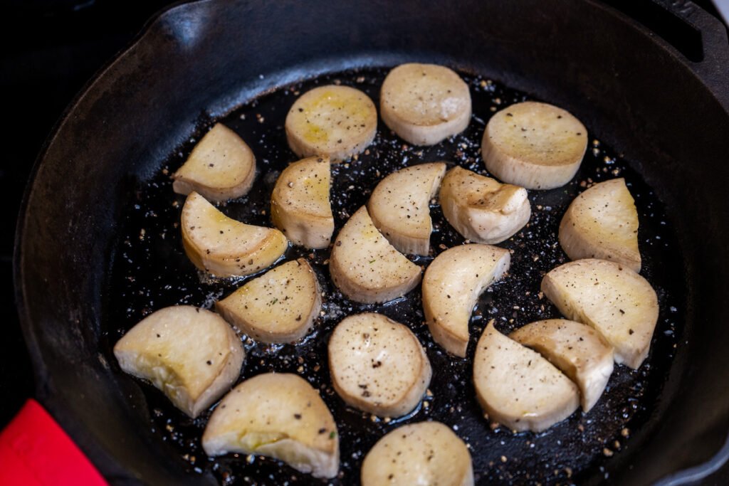 Vegan scallops in a cast iron pan seasoned with salt and pepper.