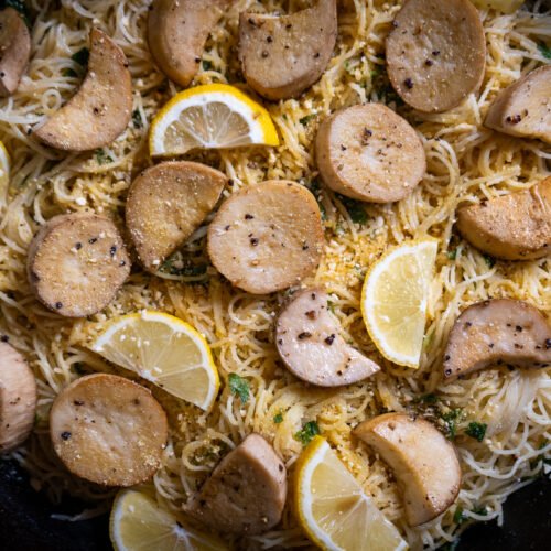 Close up of angel hair pasta dish with vegan scallops in a cast iron pan.