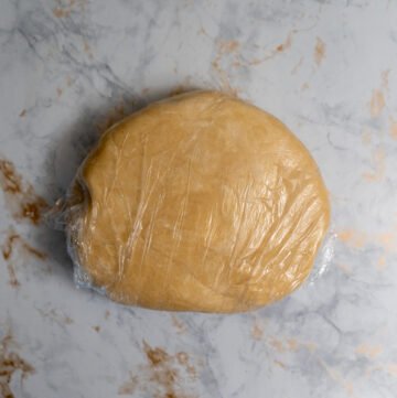 A ball of pie dough wrapped in plastic wrap