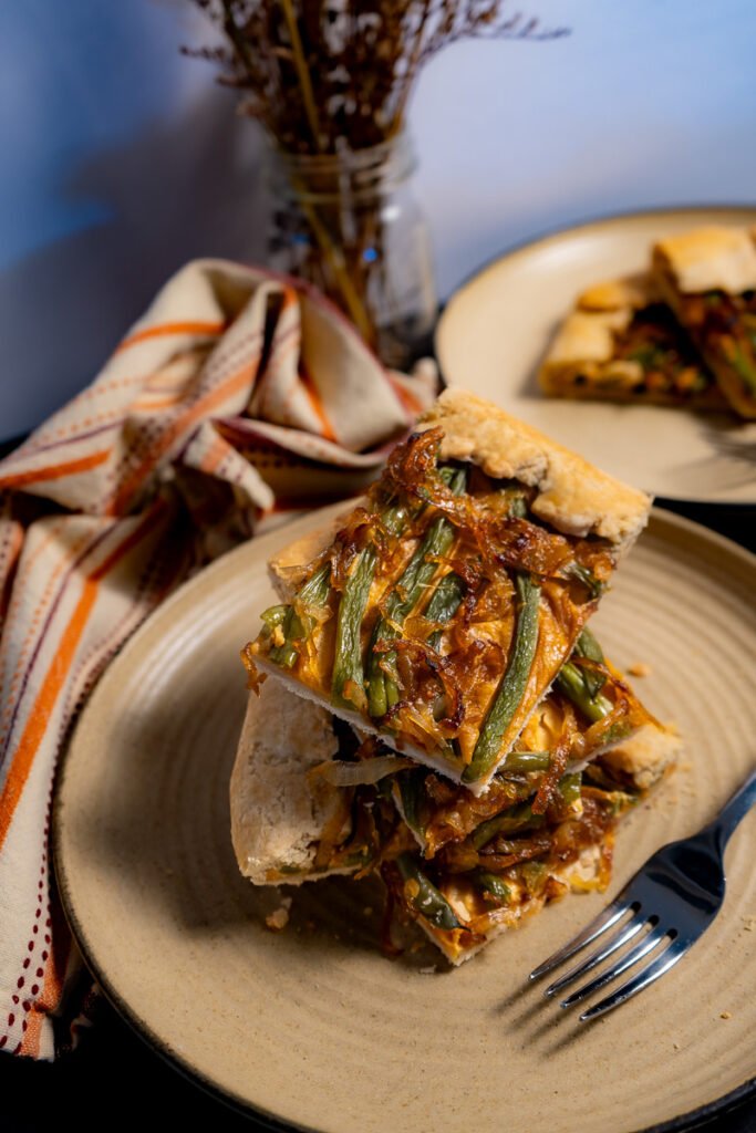 A stack of pieces of the green bean and caramelized onion galette on a plate.