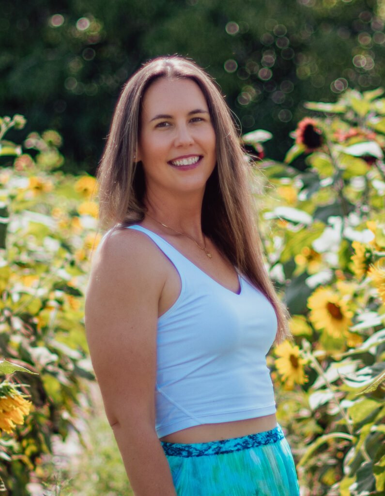 A woman in a white top standing in a sunflower field.