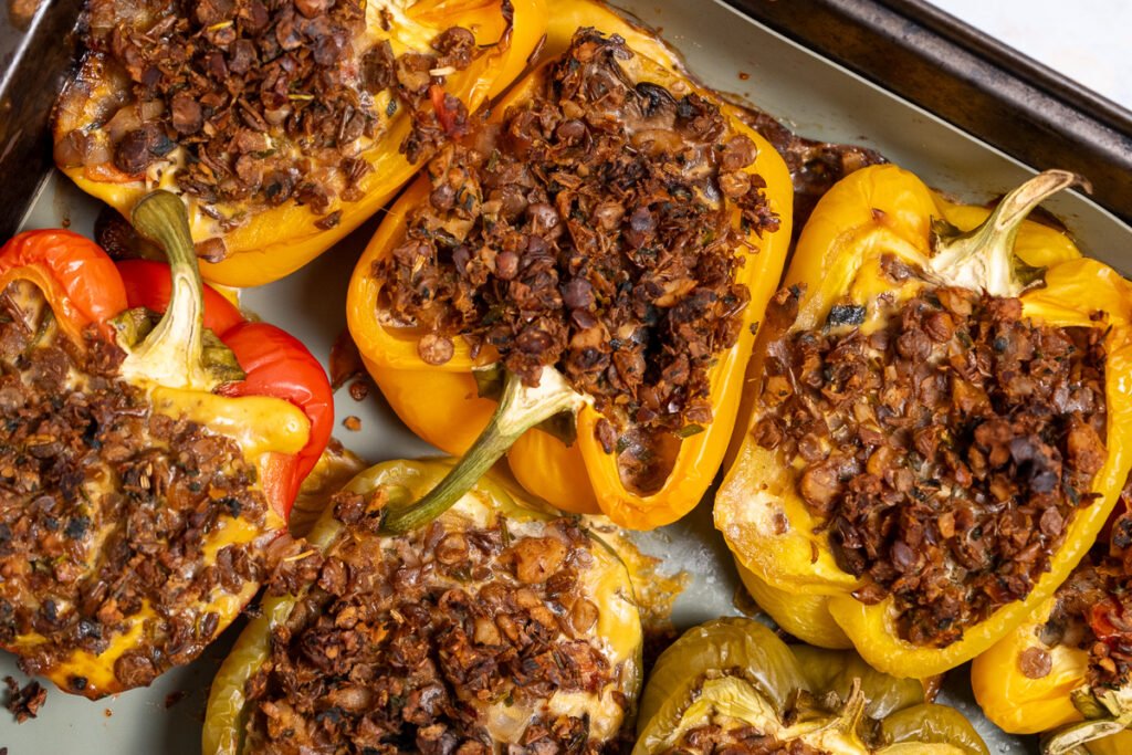 Close up of bell peppers cut in half lengthwise and stuffed with frittata and vegan sausage cooked on a baking sheet.