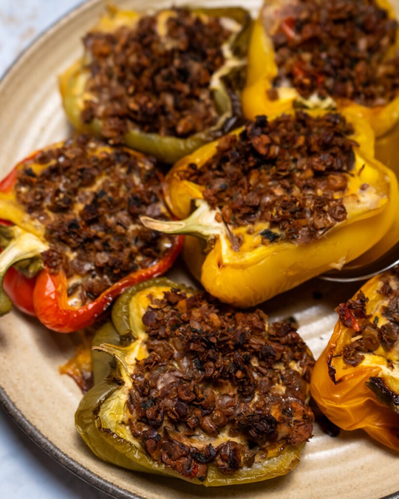 Close up of bell peppers cut in half lengthwise and stuffed with frittata and vegan sausage on a plate.