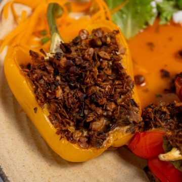 Close up of a bell pepper cut in half lengthwise and stuffed with frittata and vegan sausage uncooked on a baking sheet.