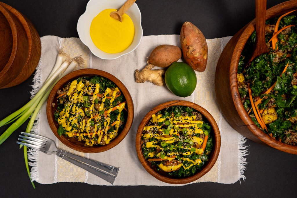 Two wooden bowls with salad in them and the golden turmeric dressing on top.