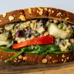 A side view of the Za'atar Chickpea Sandwich on a wooden board.