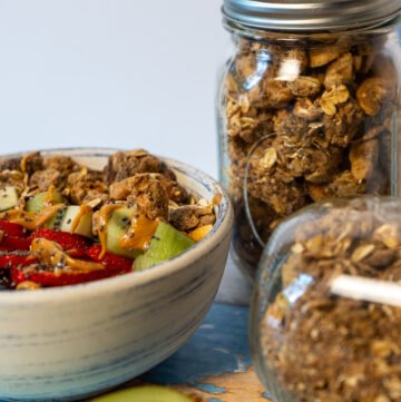 A bowl of yogurt with fruit and granola. Two jars of High Protein Vegan Granola.