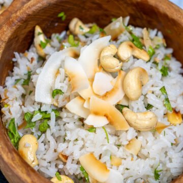 A bowl of garlic coconut rice with roasted coconut and cashews on top