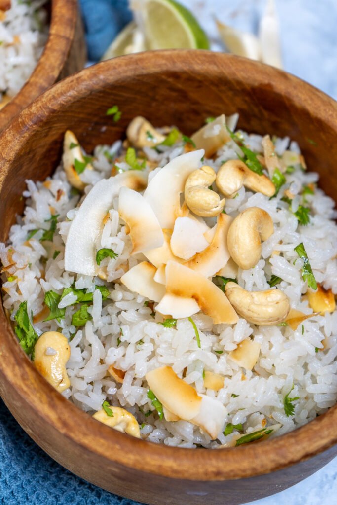 A bowl of garlic coconut rice with roasted coconut and cashews on top