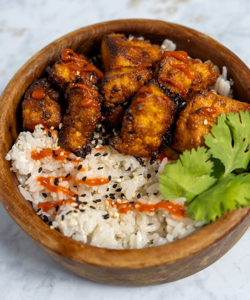 A bowl of coconut rice with Sriracha Tofu on top