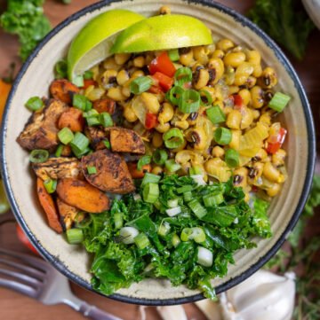 A colorful bowl of Jamaican black eyed pea curry, jerk sweet potatoes and carrots, and garlic kale.