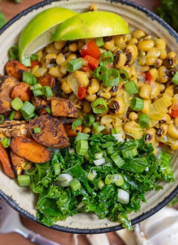 A colorful bowl of Jamaican black eyed pea curry, jerk sweet potatoes and carrots, and garlic kale.