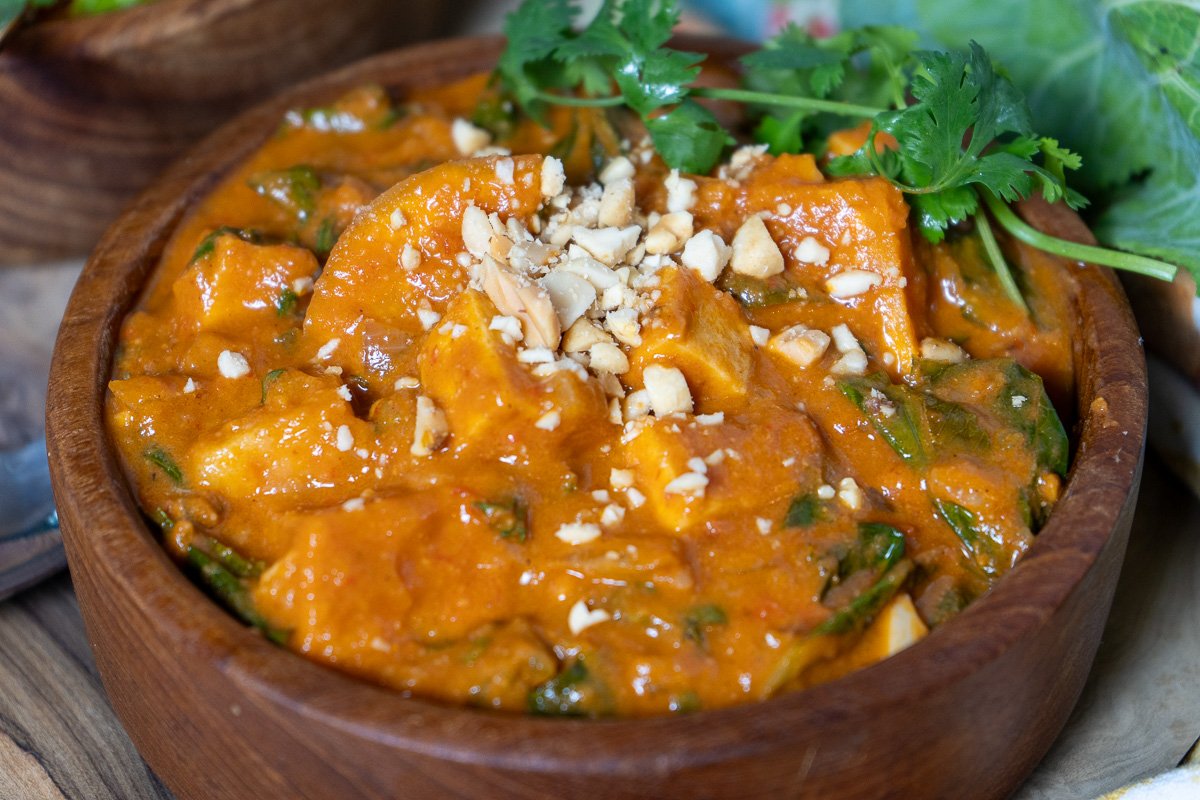 A bowl of west African tofu peanut stew in a wooden bowl.