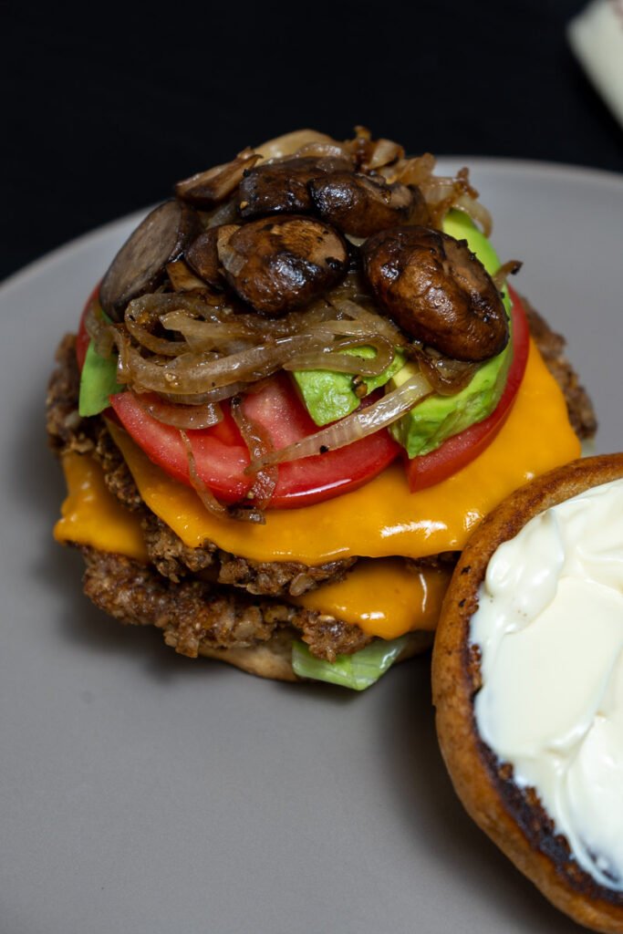 A walnut mushroom smash burger with the top bun removed to showcase the toppings.