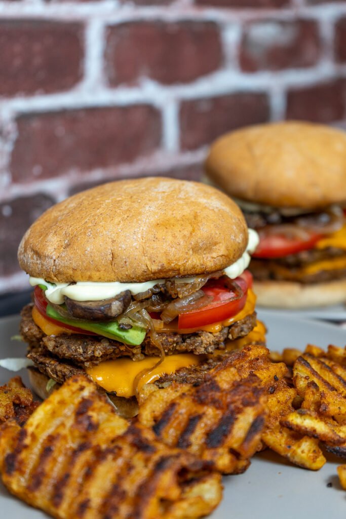 Walnut mushroom smash burger on plates with waffle fries.