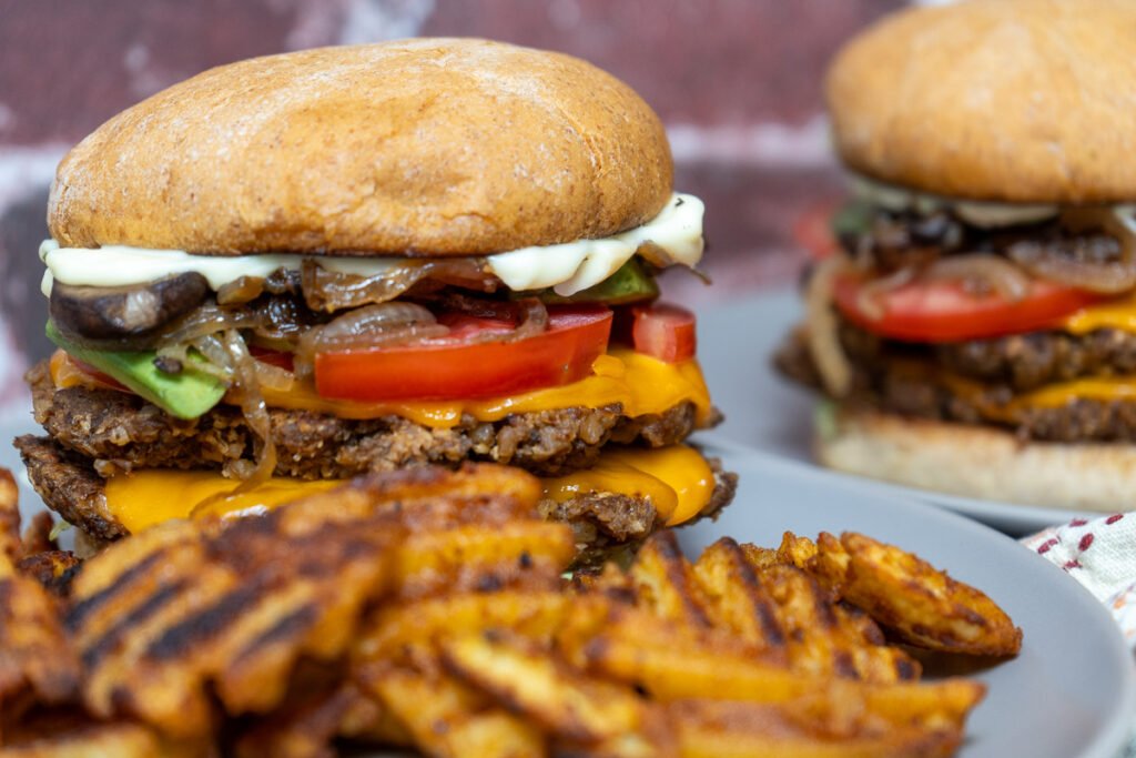 Walnut mushroom smash burger on plates with waffle fries.