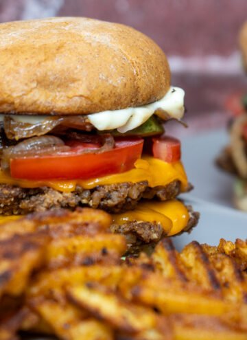 Walnut mushroom smash burger on plates with waffle fries.