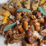 Close up of butternut squash risotto with sage tempeh and mushrooms on a plate with a fork.