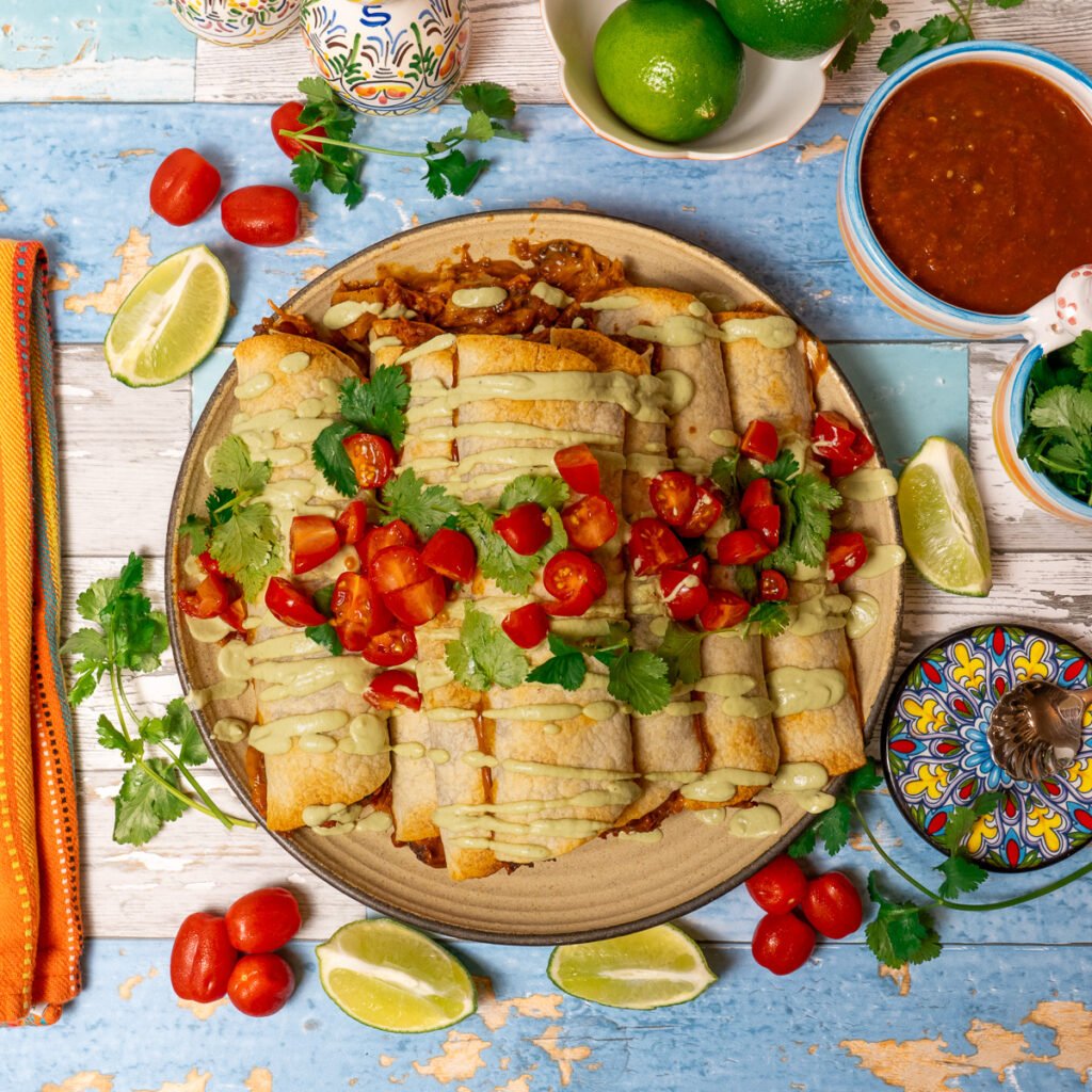 A colorful plate of 12 chipotle jackfruit taquitos.