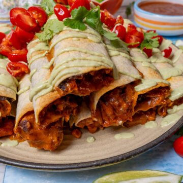 Close up of chipotle jackfruit taquitos stacked on a plate.